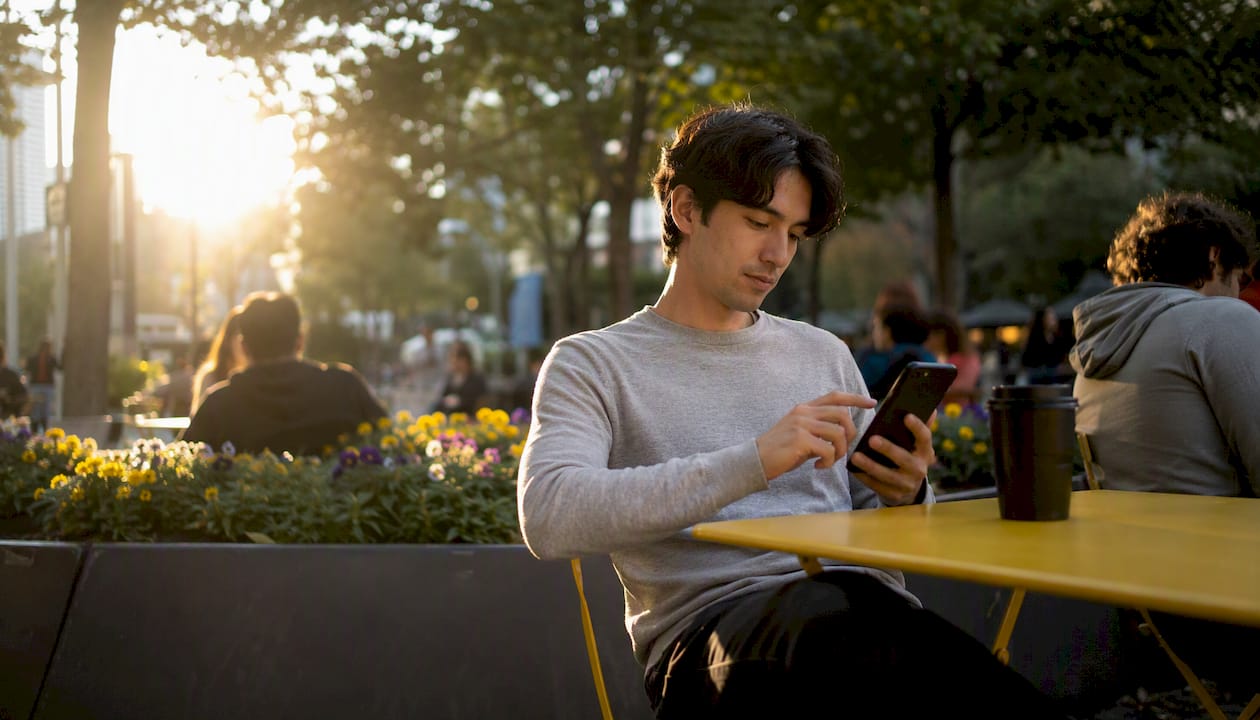 Student interacting with dark smartphone in cafe