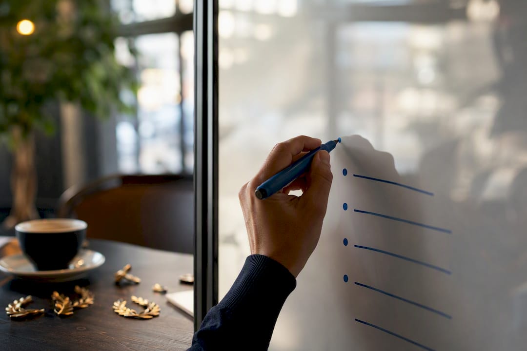 Hand writing meeting agenda on glass whiteboard